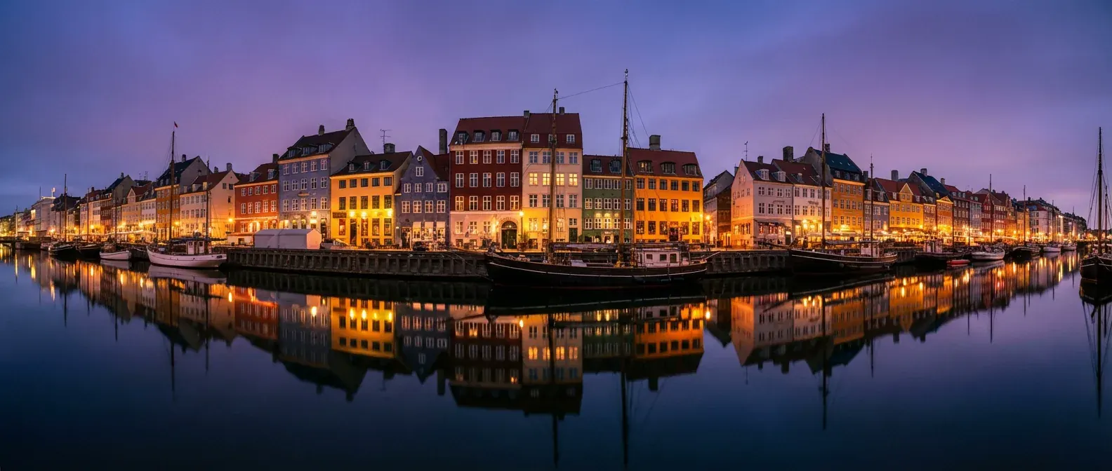 Nyhavn i København i skumringen med lys i husrækken og både i kanalen.